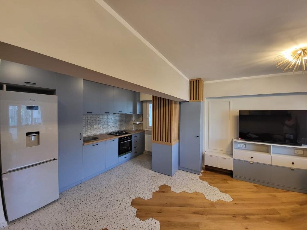 Bucătărie gri-albastru deschisă spre living, vedere de ansamblu
