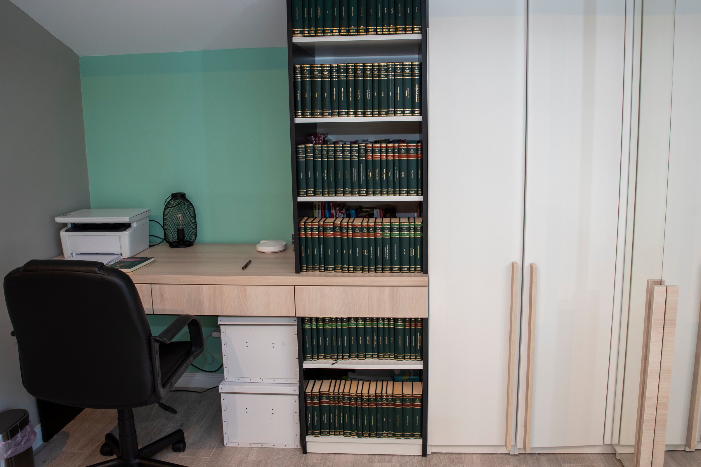 Birou cu blat de stejar lângă bibliotecă neagră și dulapuri crem