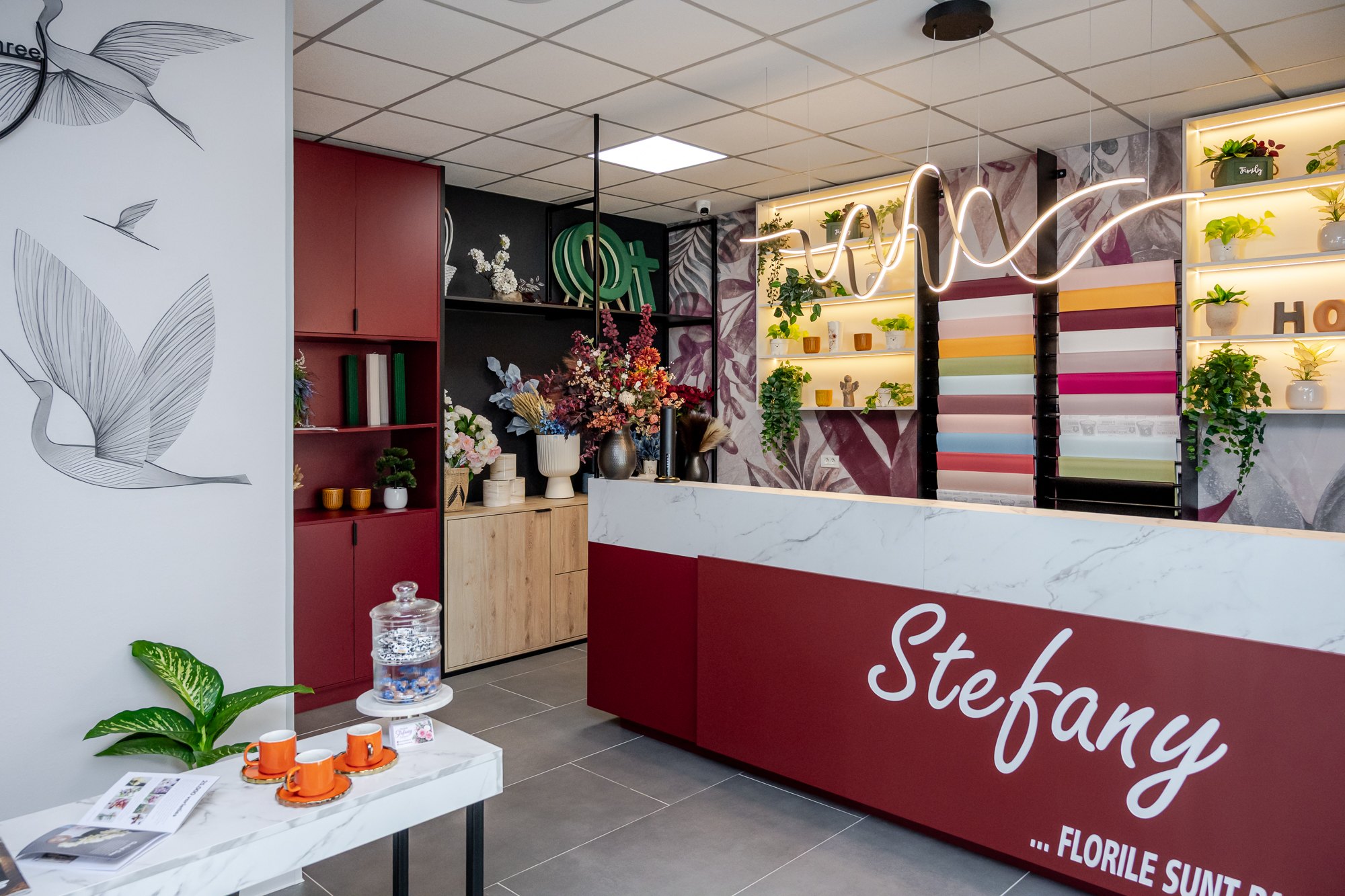Tejghea de recepție burgundy și raft cu hârtie colorată de ambalat, în spate