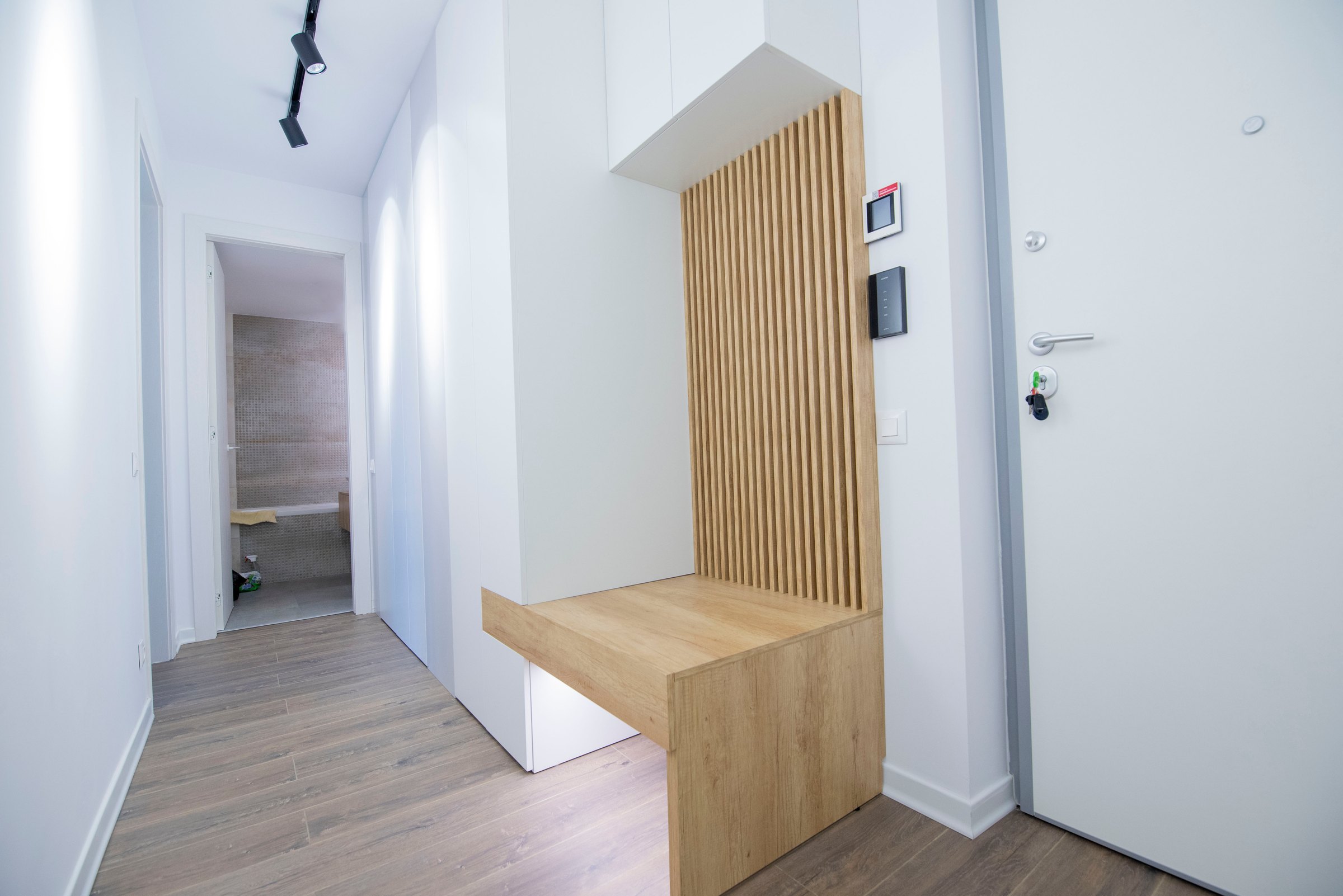 Hol cu banchetă în decor de stejar și panou cu lamele, lângă ușa de la intrare