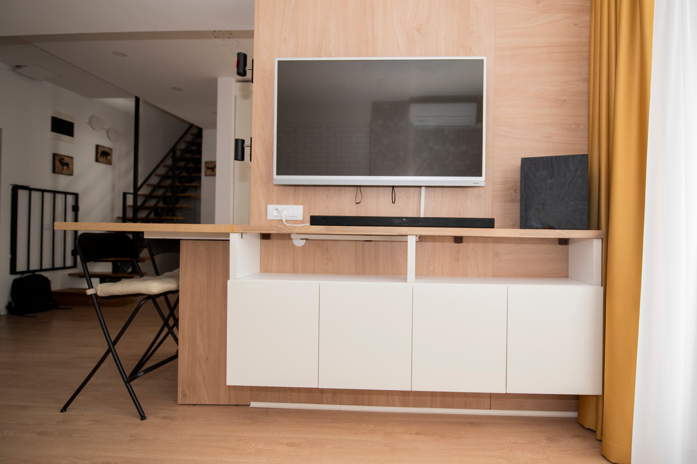 Perete TV placat cu decor de stejar, cu corpuri albe suspendate dedesubt